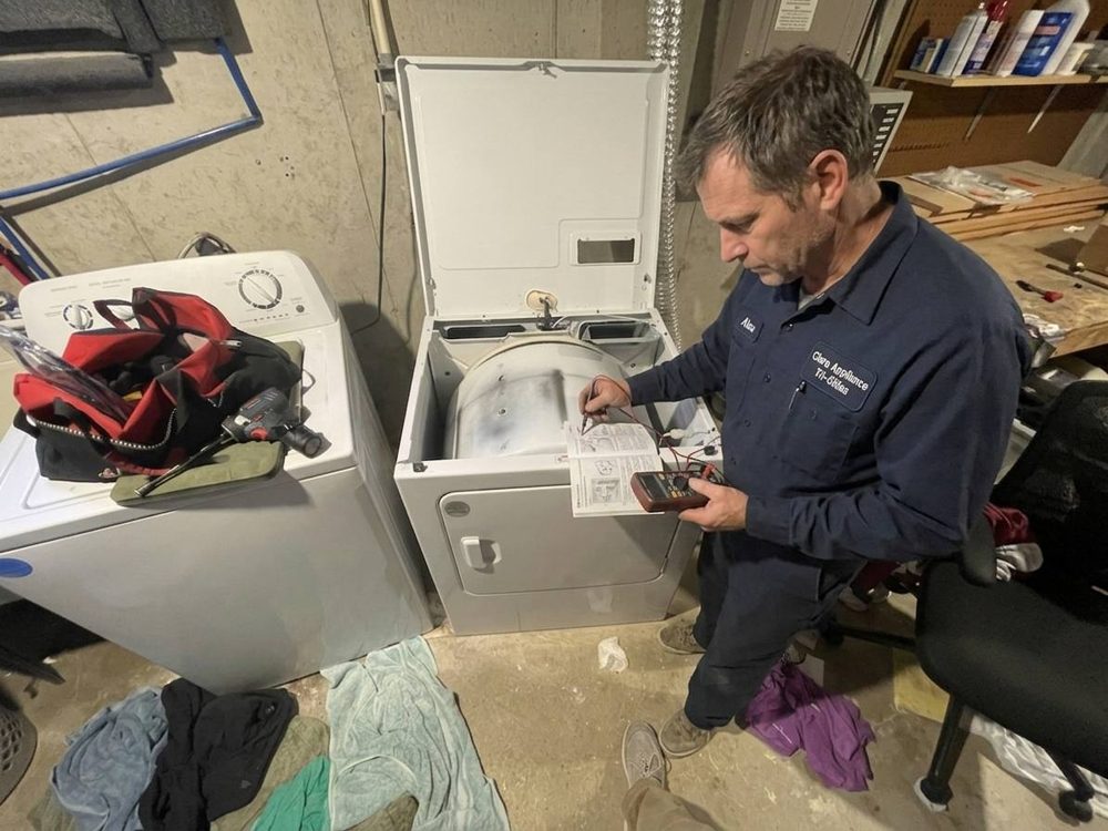 Clara Appliance technician checking a top-load dryer against the service manual